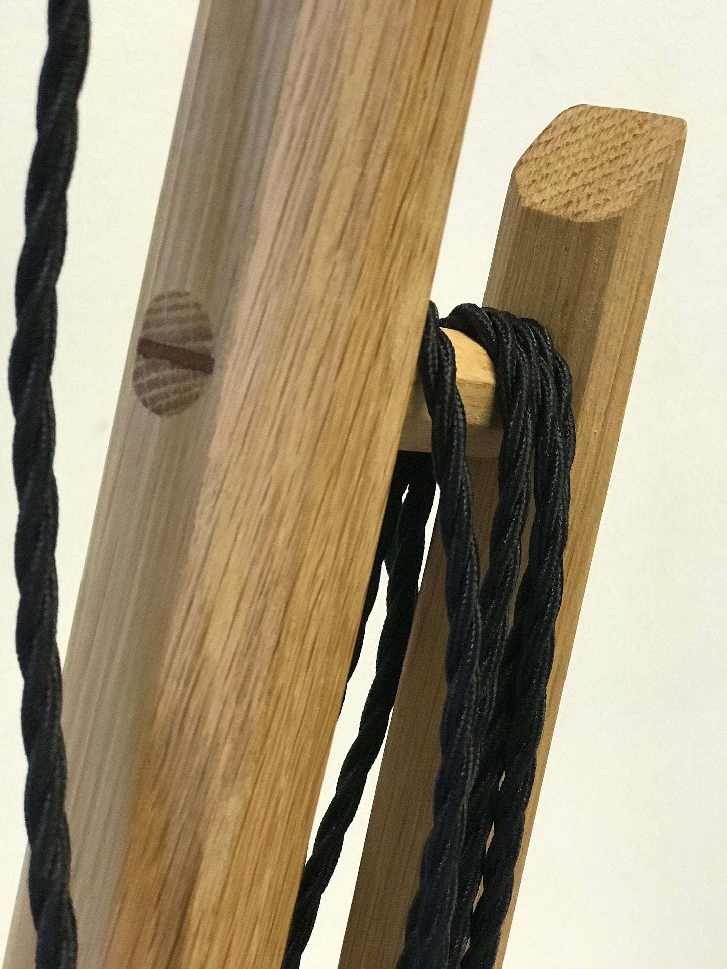 Black fabric electrical cable wound onto a rustic oak frame
