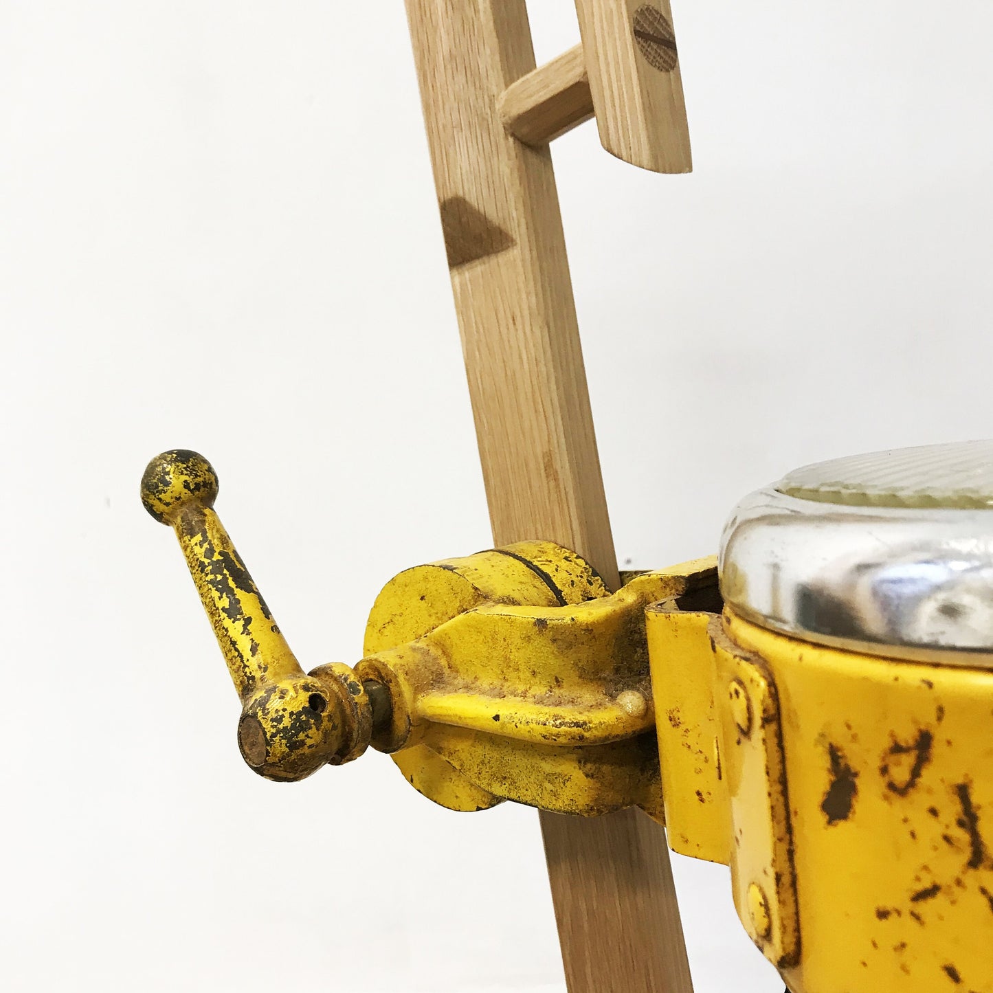 Detail of a vinage yellow spotlight clamped onto a wood oak frame