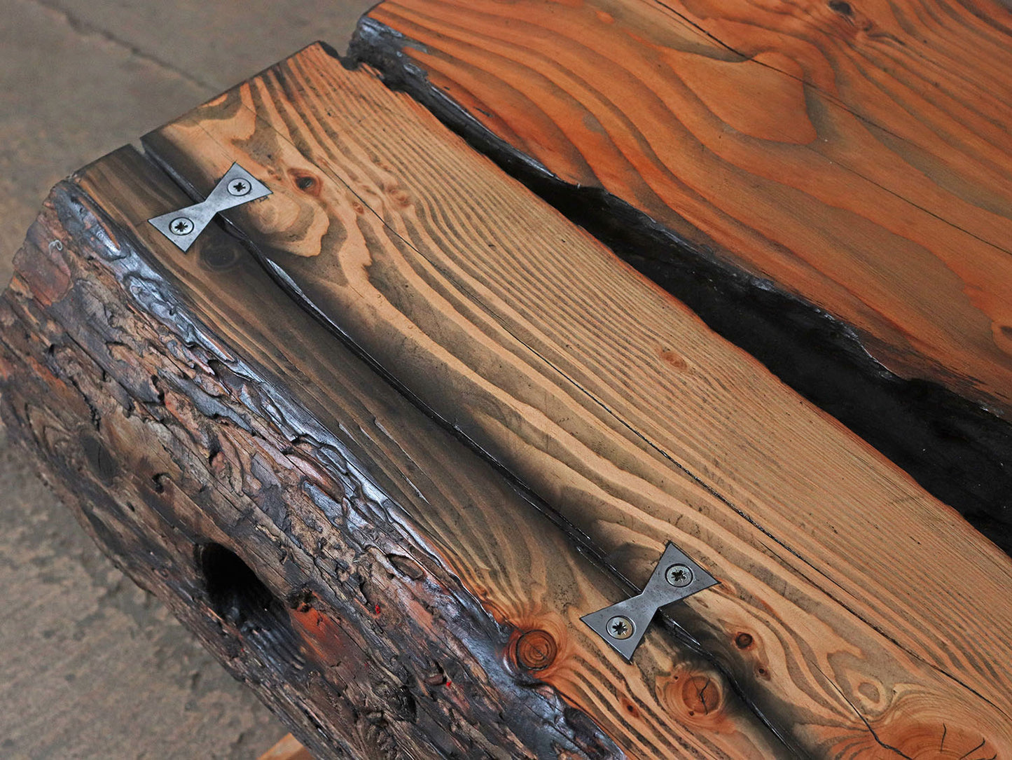 Metal bowtie joinery used to secure a large crack in a driftwood tabletop surface - the rustic aesthetic and metal have a wonderful contrast