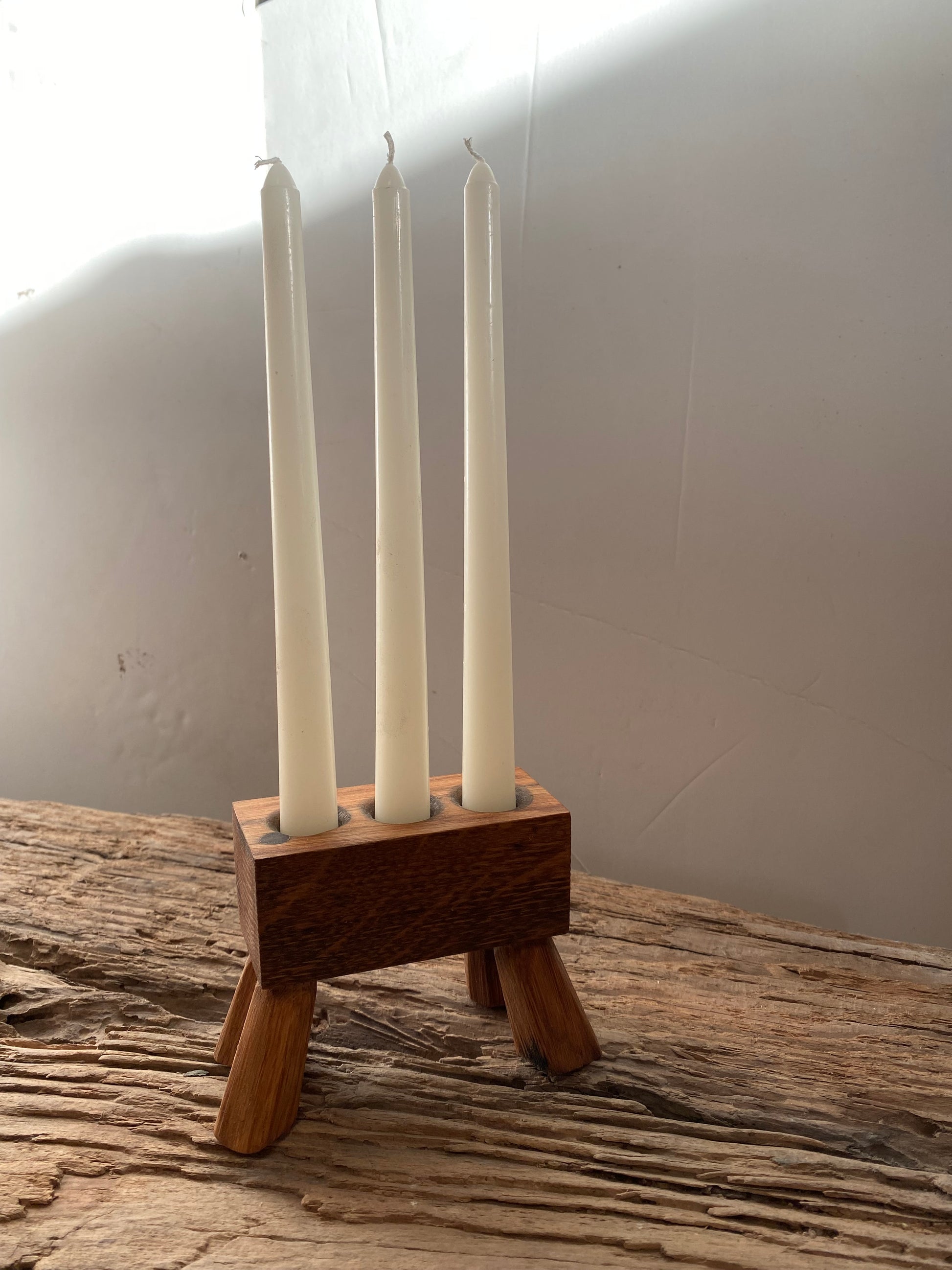 A rustic triple-candle holder stand, handcrafted from a reclaimed oak and designed with 4 legs giving the design a distinctive presence