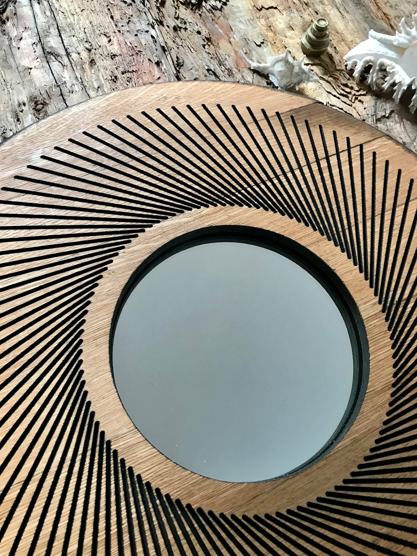 Sacred geometry-inspired oak wall mirror with a radial line pattern, handcrafted from a reclaimed whisky barrel lid. A sustainable decor piece showcasing rustic charm and natural patina