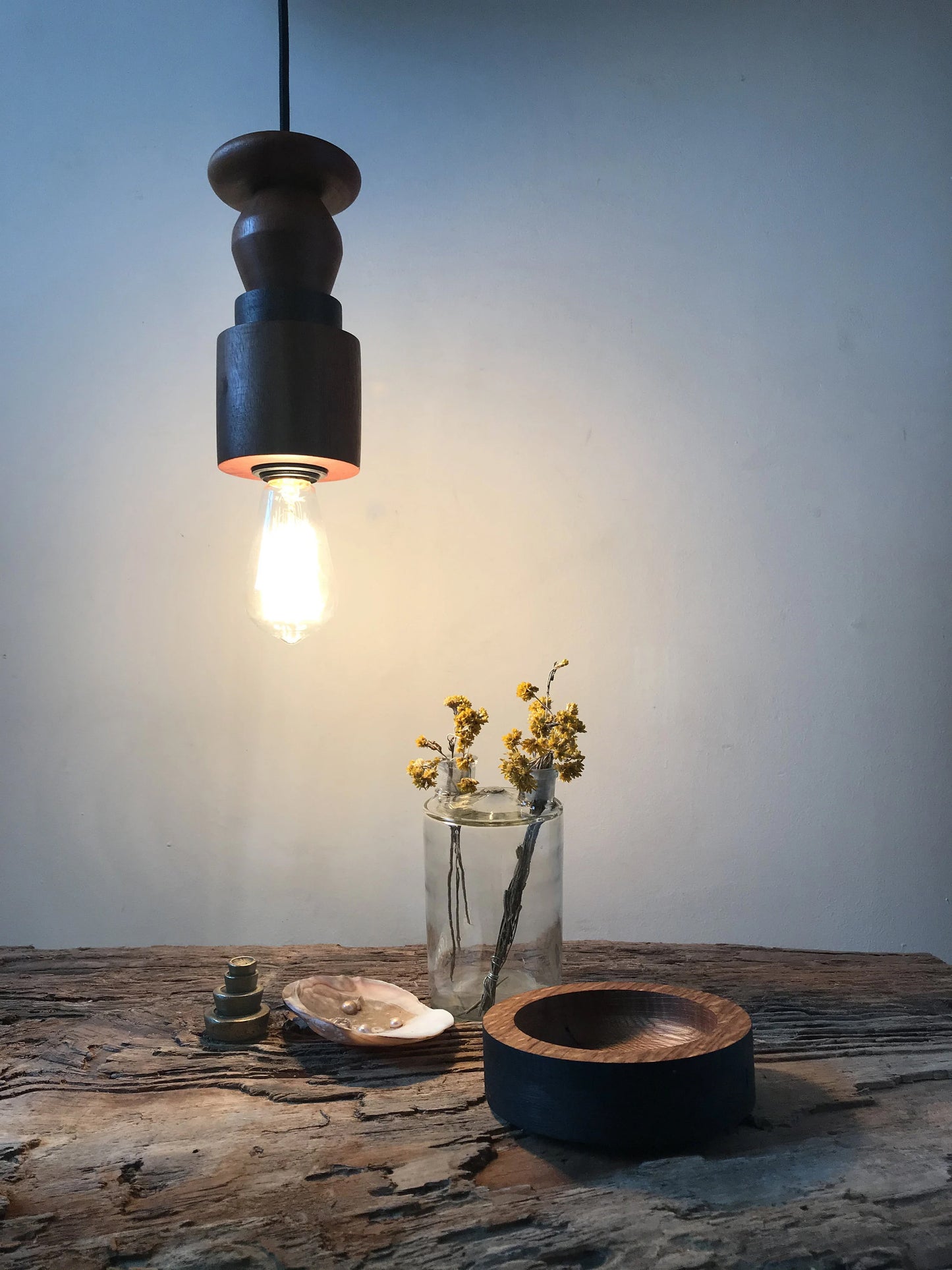 Rustic pendant light consisting of hardwood geometric beads threaded onto a lighting fitting with a filament bulb